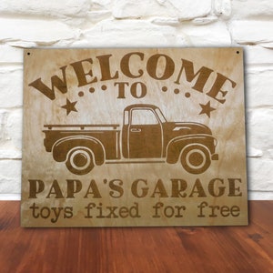 Può includere: Cartello in legno con un camion vintage e il testo "Benvenuti al garage di papà, giocattoli riparati gratuitamente".