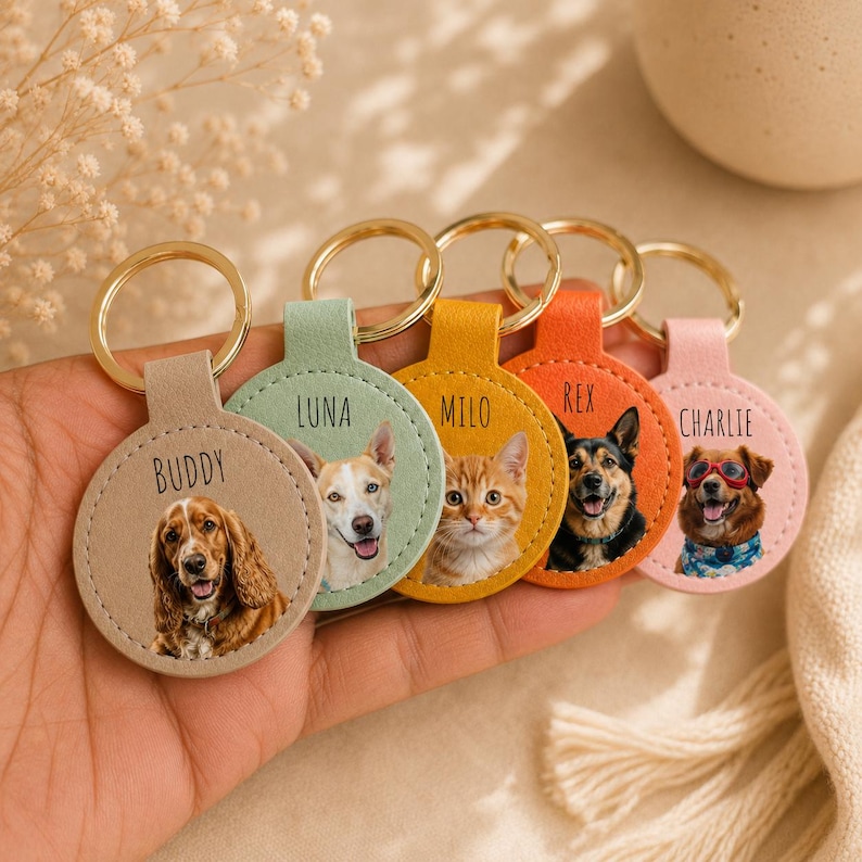 May include: A collection of personalized pet keychains. Each keychain features a circular design with a pet's photo and name. The keychains have different colored backgrounds and gold-colored key rings. The names on the keychains are Buddy, Luna, Milo, Rex, and Charlie.