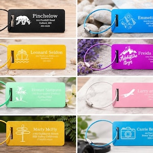May include: A selection of colourful luggage tags, each with a unique design and name. The tags display images of a bear, mountains, a ship, a mountain with text, palm trees, an airplane, road signs, and a camera. Each tag has a metal loop.