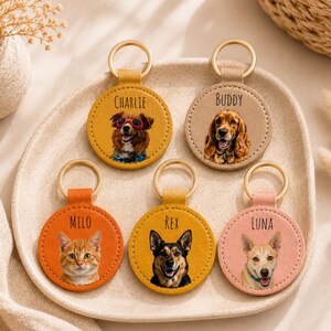 May include: A collection of personalized pet keychains. Each keychain features a circular leather design with a gold-colored ring. The keychains display portraits of dogs and a cat, with names like "Charlie," "Buddy," "Milo," "Rex," and "Luna."