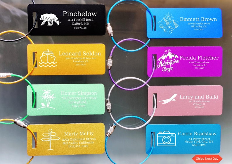 May include: A selection of colourful luggage tags, each with a different design and name. The tags feature illustrations of a bear, mountains, a ship, palm trees, a signpost, a plane, and a camera. Each tag includes a name, address, and phone number.
