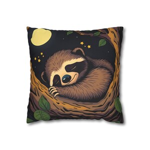 Può includere: Cuscino quadrato con un bradipo dei cartoni animati che dorme in un albero. Il bradipo è marrone con un viso color crema ed è appollaiato su un ramo. Lo sfondo è un cielo notturno scuro con una luna gialla e stelle.