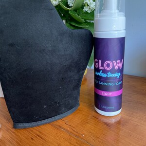 May include: A black tanning mitt and a bottle of self tanning foam labeled "GLOW sunless tanning SELF TANNING FOAM LIGHT 7 FL OZ (207ml)"