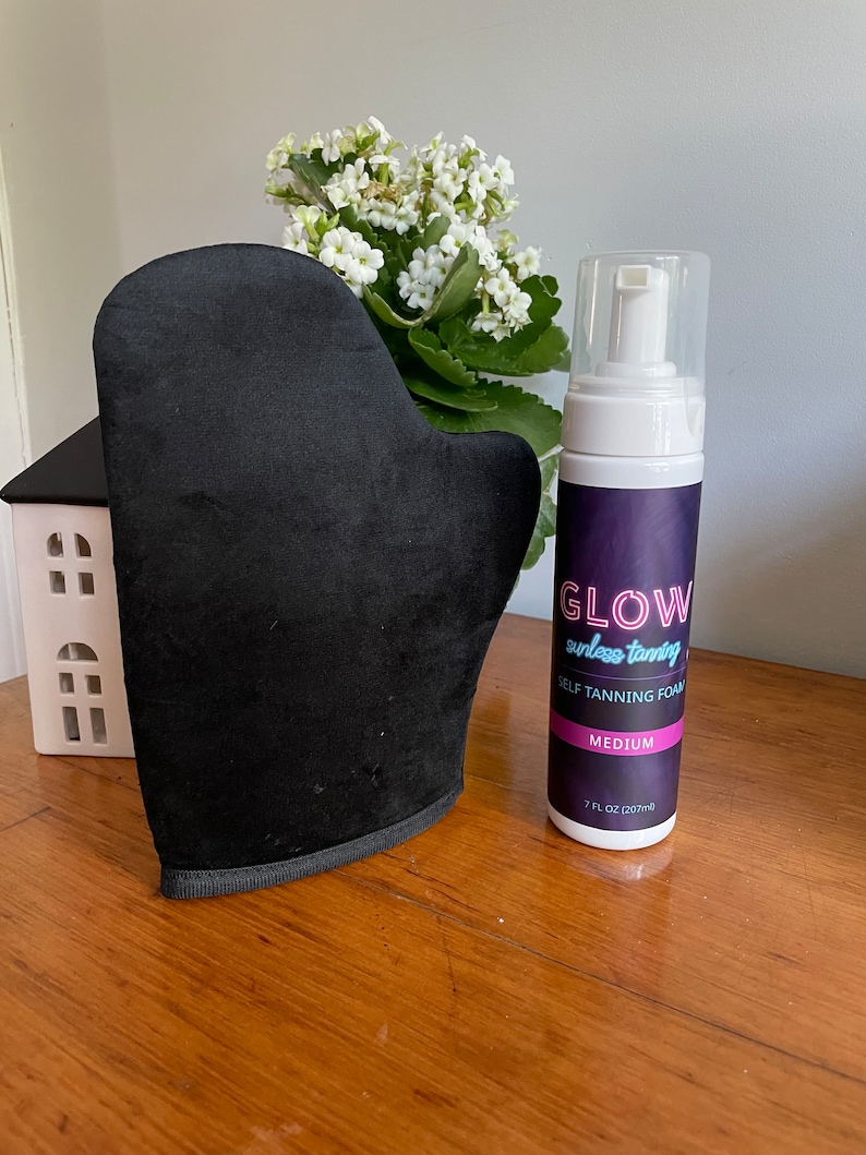 May include: A black self-tanning mitt and a bottle of self-tanning foam labeled "GLOW sunless tanning SELF TANNING FOAM MEDIUM 7 FL OZ (207 ml)"