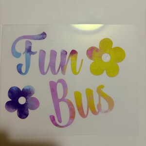 May include: A clear decal sheet featuring the text Fun Bus in a cursive font with a watercolor gradient of blue, purple, pink, and yellow. The design includes two five-petal flowers, one in solid yellow and one in a dark purple watercolor pattern.