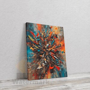 Peut inclure: Impression sur toile d'art abstrait représentant une explosion de couleurs. L'œuvre présente une explosion centrale de teintes orange, rouge et jaune, avec des fragments bleus et dorés dispersés. La toile est appuyée contre un mur gris clair sur une surface en bois.