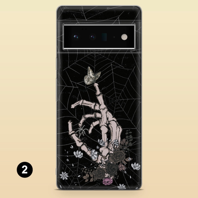 May include: A black phone case with a skeleton hand holding a butterfly, surrounded by a spider web and flowers.