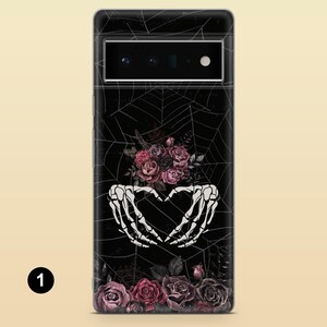 May include: Black phone case with a spiderweb design and a bouquet of pink and purple roses. Two white skeleton hands are forming a heart shape above the roses.