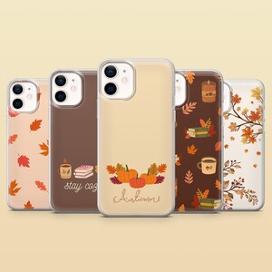May include: Five clear phone cases featuring autumn-themed designs. Patterns include orange and red fall leaves, pumpkins with the text 'Autumn', and a brown case with books, a mug, and the text 'stay cozy' printed on the back surfaces.