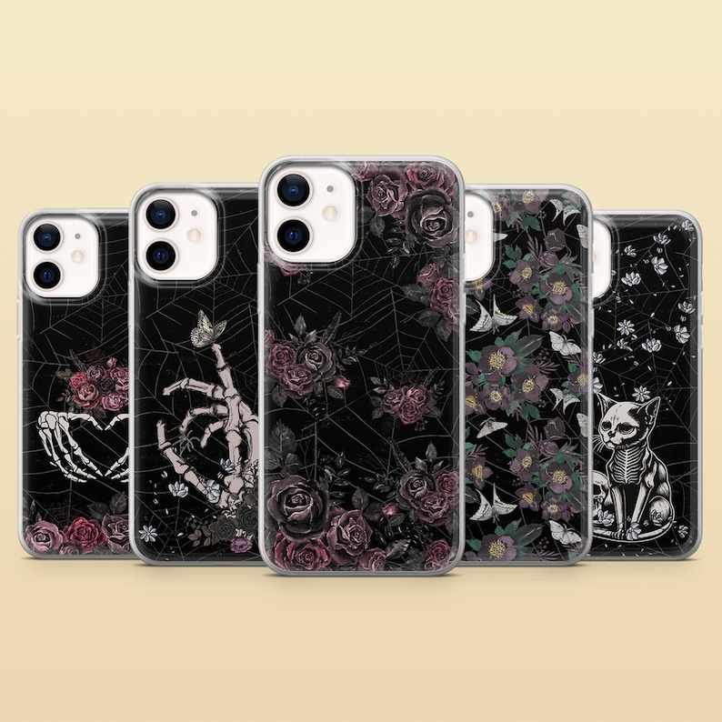 May include: Five clear phone cases with different gothic floral and skeletal designs. The designs include a skeleton hand holding a heart, a skeleton hand holding a butterfly, a spider web with roses, a floral pattern with birds, and a skeleton cat.
