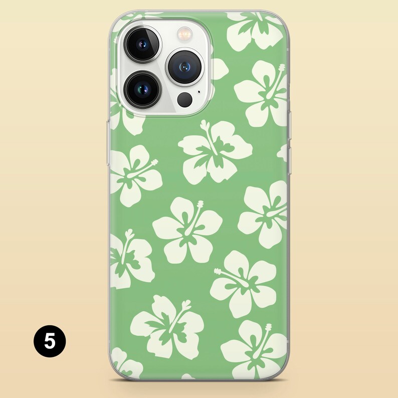 May include: A clear phone case with a green background and white hibiscus flowers. The case is designed for an iPhone 13 Pro Max.