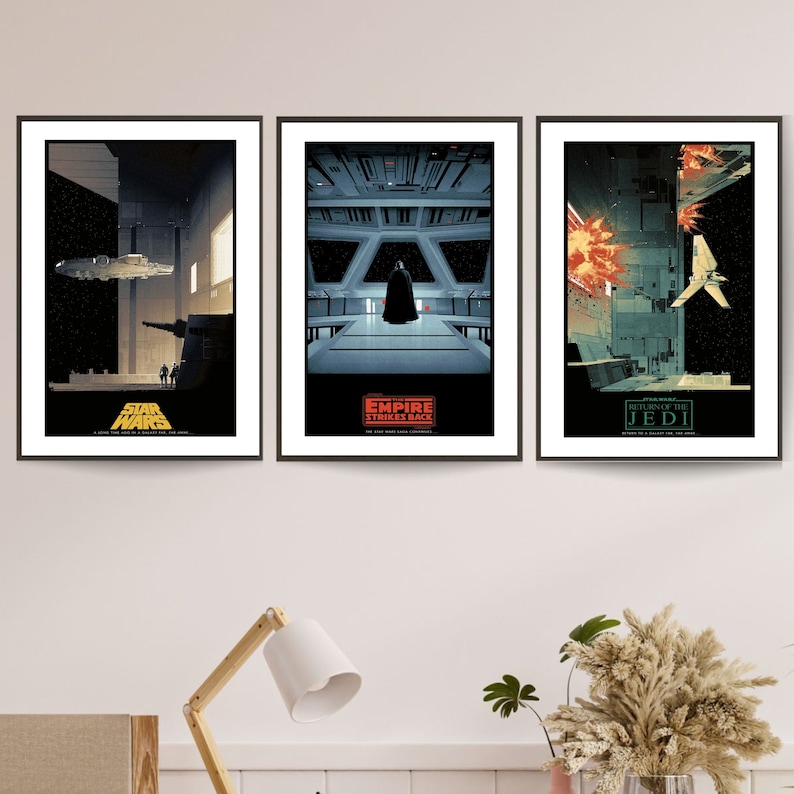 May include: Three framed movie posters for the Star Wars trilogy. The posters are black and white with red and yellow accents. The first poster is for "Star Wars: A New Hope", the second is for "The Empire Strikes Back", and the third is for "Return of the Jedi".