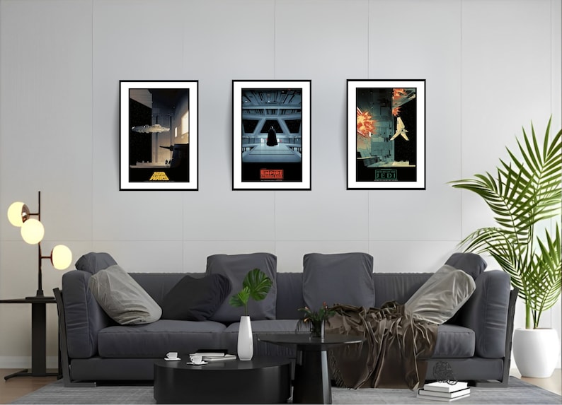 May include: Three framed Star Wars movie posters on a white wall. The posters are in black frames and feature minimalist designs of scenes from the movies. The posters are titled "Star Wars", "The Empire Strikes Back", and "Return of the Jedi".
