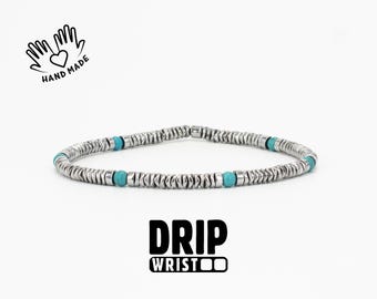 May include: A silver bracelet with turquoise beads. The bracelet is made of small, round, silver-colored metal beads. The bracelet has a simple design and is displayed on a white background. The text "HAND MADE" and "DRIP WRIST" are also visible.
