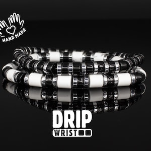 May include: A black and white beaded bracelet with the words "DRIP WRIST" printed on a black background.