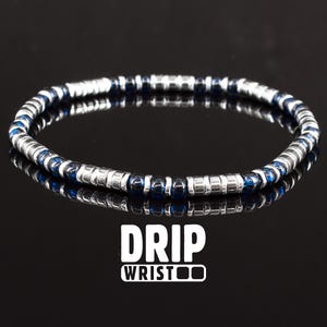May include: A silver and blue beaded bracelet with the text "DRIP WRISTOO" on a black background.