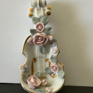 May include: A white ceramic mug with a black handle and the text "But First, Coffee" in a handwritten style. The mug is on a white surface. The mug is approximately 4 inches tall.