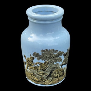 Puede incluir: Un tarro de cerámica azul claro con un diseño dorado de una escena de caza. La escena representa a un grupo de personas cazando con perros y un caballo.