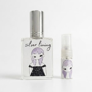Silver Lining eau de parfum bottle and roller; lavender-haired label art on glass with silver cap; indie botanical perfume.