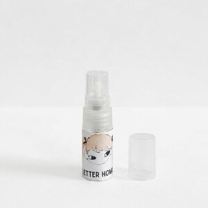 Pu&ograve; includere: Un piccolo flacone spray in plastica trasparente con tappo rimovibile. Il flacone presenta un'etichetta bianca con un'illustrazione disegnata a mano di un volto con capelli biondi e il testo nero parziale "LETTER HOM" stampato sul davanti.