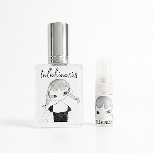 May include: A rectangular glass perfume bottle with a silver cap and a smaller cylindrical glass spray vial. Both containers feature a black and white ink illustration of a person with pigtails and the text telekinesis printed on the labels.