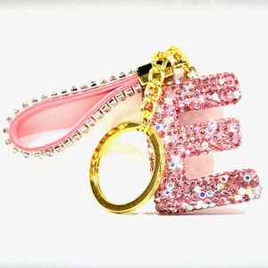 May include: Pink letter E keychain with rhinestones and a gold chain and ring.
