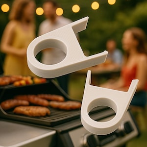 Peut inclure: Deux accessoires Optigrill blanc cassé sont présentés. Ils ont une poignée circulaire et une extension rectangulaire. L'arrière-plan montre un barbecue avec des saucisses et des personnes. Le mot OPTIGRILL est en haut.