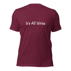 May include: A maroon t-shirt with the white text "It's All Write" across the chest. The short-sleeved shirt is made of a soft material and is suitable for casual wear. The shirt is a solid color.