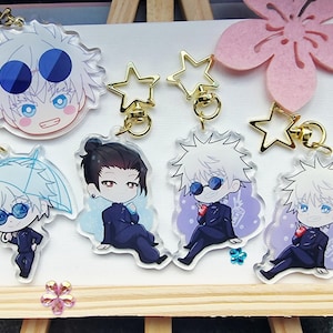 May include: A collection of anime-style acrylic keychains featuring various characters. Each keychain has a unique design, with gold star-shaped clasps. The characters have distinct hairstyles and outfits, with vibrant colors and detailed facial expressions.