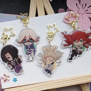 Könnte beinhalten: Vier Schlüsselanhänger mit Anime-Charakteren. Jeder Schlüsselanhänger zeigt ein anderes Charakterdesign mit leuchtenden Farben und detaillierten Kunstwerken. Die Schlüsselanhänger sind aus klarem Acryl gefertigt und haben goldfarbene sternförmige Anhänger.