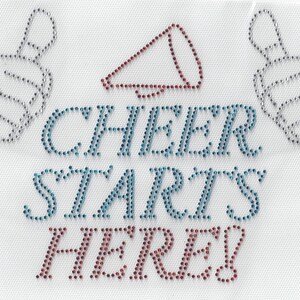 May include: A white background with a blue and red diamond-shaped design with two silver thumbs up on either side. The text "CHEER STARTS HERE!" is in blue and red rhinestones.
