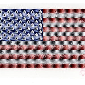 May include: A close-up of a red, white, and blue American flag made of rhinestones. The flag is on a white background.