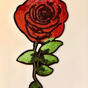 May include: A red sequined rose with green sequined leaves and a black outline.