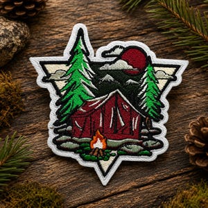 May include: A triangular embroidered patch featuring a red tent and a campfire in the foreground, flanked by two green pine trees. The background displays a dark sky with a large red moon, white clouds, and mountain silhouettes, all outlined in white.
