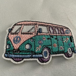 May include: Embroidered patch featuring a colorful vintage van. The van is split into pink and teal sections, adorned with floral and peace sign details. The patch has a white border.