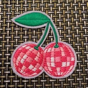 May include: A pink and white gingham cherry with a green leaf embroidered patch.