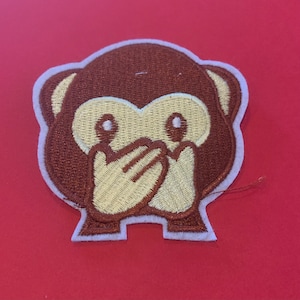 May include: Embroidered brown monkey patch with a white hand covering its mouth, representing the "See no evil" monkey from the "Three Wise Monkeys" proverb.
