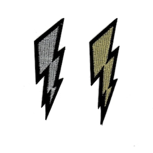 May include: Two embroidered iron-on patches in the shape of a lightning bolt. One patch is silver and the other is gold.