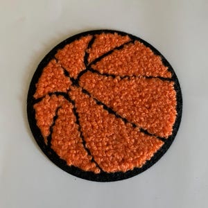 May include: A round orange and black felt basketball patch.