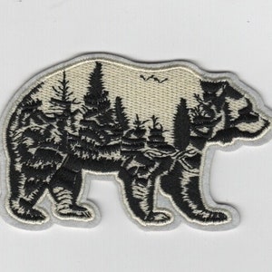 May include: Black embroidered patch of a bear silhouette with a forest scene inside. The bear is standing on a white background.