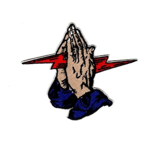 May include: Embroidered patch featuring a pair of hands clasped in prayer with a red lightning bolt behind them. The hands are beige, the lightning bolt is red, and the sleeves are blue.
