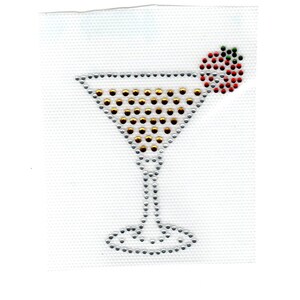 May include: A rhinestone martini glass design. The glass is outlined in silver rhinestones, with gold rhinestones filling the center. A cluster of red and green rhinestones represents a cherry garnish. The design is on a white background.