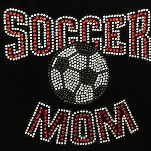 May include: Red and white rhinestone design that says "Soccer Mom" with a black and white soccer ball in the middle.