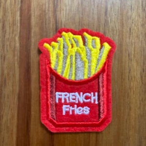 May include: Red felt patch with a yellow embroidered image of french fries in a red container. The text "French Fries" is embroidered in white on the container.