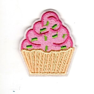 May include: Pink cupcake with green sprinkles and a light brown cupcake liner. The cupcake is embroidered on a white fabric.