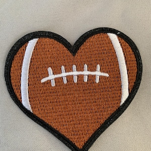 May include: A brown and white heart-shaped patch with an embroidered football design.