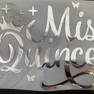 May include: Silver glitter iron-on patch with the text "Mis Quince" and a crown. The patch is decorated with small stars and butterflies.