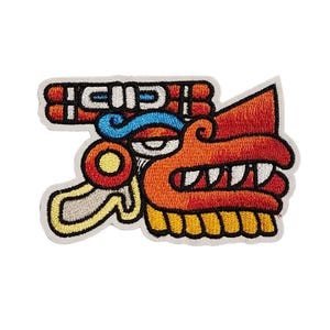 May include: Embroidered patch featuring a stylized, colorful Aztec dragon head. The design includes orange, red, blue, yellow, and white details, with a cream-colored border. The patch is likely for clothing or accessories.