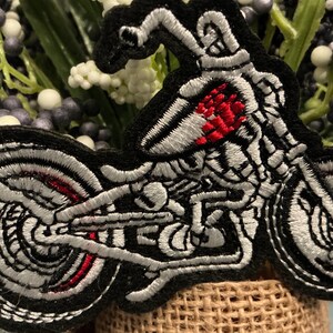 Puede incluir: Parche bordado con un dise&ntilde;o de motocicleta esqueleto. El parche tiene un borde negro con detalles blancos y rojos, que muestran el marco esquel&eacute;tico y el motor de la motocicleta. Las ruedas y el cuerpo est&aacute;n intrincadamente cosidos.