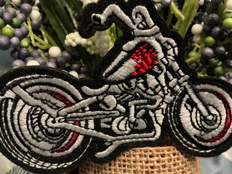 Puede incluir: Parche bordado con un dise&ntilde;o de motocicleta esqueleto. El parche tiene un borde negro con detalles blancos y rojos, que muestran el marco esquel&eacute;tico y el motor de la motocicleta. Las ruedas y el cuerpo est&aacute;n intrincadamente cosidos.
